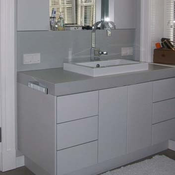 Bathroom with a gray vanity cabinet with an inset white ceramic sink and push-to-open doors and 6 drawers