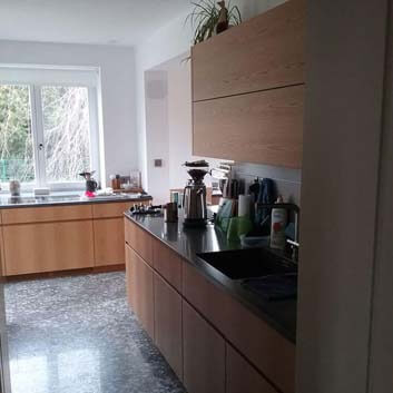 Contemporary warm wooden kitchen with Corian countertop and ribbed handles on the kitchen fronts.
