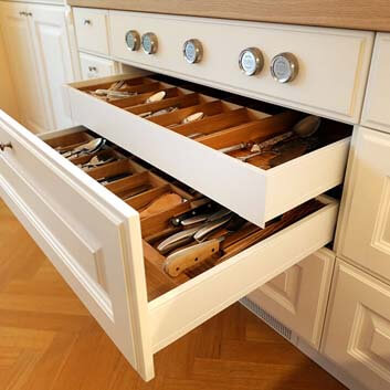 Drawer solution for a large cutlery and silverware collection (internal drawers), traditionally grooved fronts, silver knobs as handles, and Bora stove controls