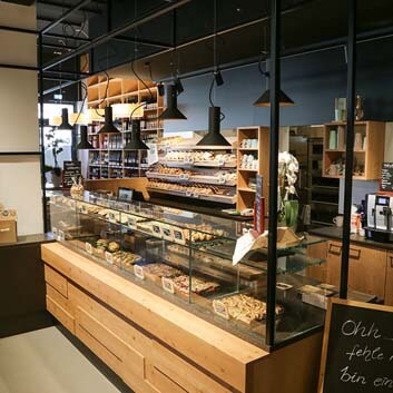 Organic supermarket in Germany, natural wood bakery counter with glass showcase, open slanted bread shelves, original bread counter design