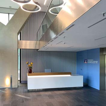 Bank counter, metal plinth, Corian and wooden top, blue glass panels on the walls.