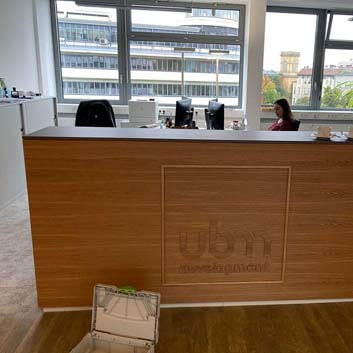 Small office counter with continuous wood grain pattern, wood-like logo glued to the vertical surface, dark top.