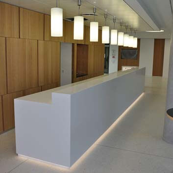 Long, minimalist, white block counter in an office area made of Corian.