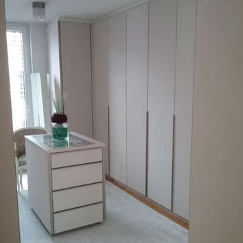 Dressing room with upholstered closet doors and freestanding glass-top cabinet holding the contents of the top drawer