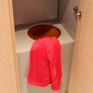 Eine Lösung für die Wäsche – ein in einem Kleiderschrank versteckter Durchbruch zur Waschküche, die sich unterhalb des Badezimmers befindet