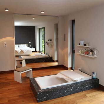 Zeitgenössisches Schlafzimmer mit einer in den Holzboden eingelassenen Badewanne mit Corian-Einfassung 