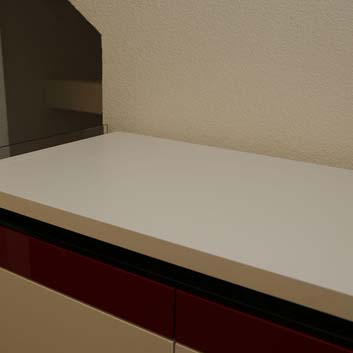 Weißes Küchenelement mit einem roten Streifen oben auf den Küchenfronten, mit einem geschlossenen oberen Deckel, um die Küche zu verbergen und das Element wie einen Schrank aussehen zu lassen