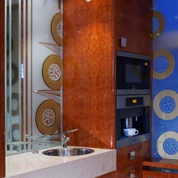 Hochmoderne, furnierte, glänzende Büroküche mit handwerklichen Griffen, eingebauter Miele-Mikrowelle und Kaffeemaschine, Corian-Arbeitsplatte und silberfarbener Küchenspüle