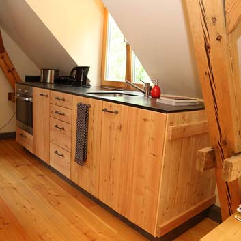 Küche aus Naturholz mit sichtbarer Holzstruktur mit Corian Black-Strukturplatte, eingelassener Spüle und Backofen