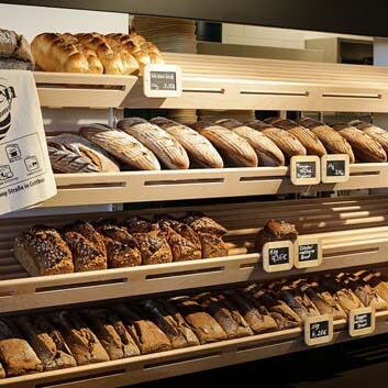 Maßgeschneidertes, offenes, geneigtes Holzregal für Brot, Bio-Supermarkt in Deutschland
