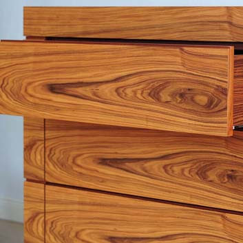 Detailbild einer offenen Vollholzschublade eines wunderschön furnierten Sideboards mit sich wiederholender Holzstruktur auf 3 Schubladenebenen