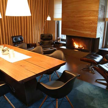 Wohnbereich, großer Kamin, Lounge Chairs von Eames, Vitra, Naturholzwand, langer, klobiger Holztisch