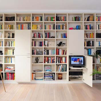 Aufbewahrungssystem Breite Wand zu Wand, Höhe Decke bis Boden, offene Regale für Bücher und zwei Einheiten mit 2 Türen, eine Tür offen mit verdecktem Fernseher auf einem herausziehbaren Tablett